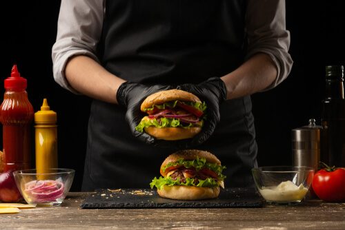 Chef Prepares a Burger, a Hamburger. On a Background With Ingredients