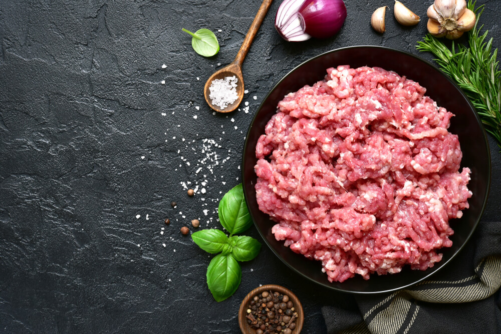 Homemade Minced Meat in a Black Bowl Over Dark Slate or Stone Background With Ingredients for Making.