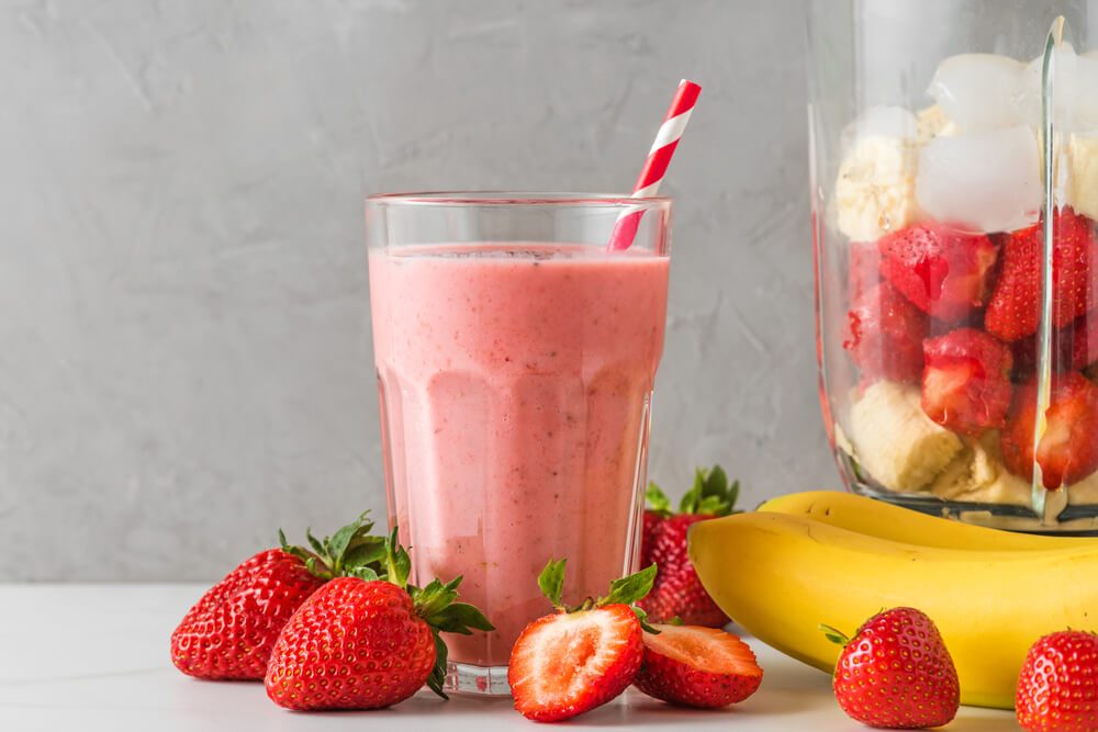 Glass of Healthy Smoothie or Milkshake Made of Strawberry, Banana, Almond Milk With Blender and Straw.
