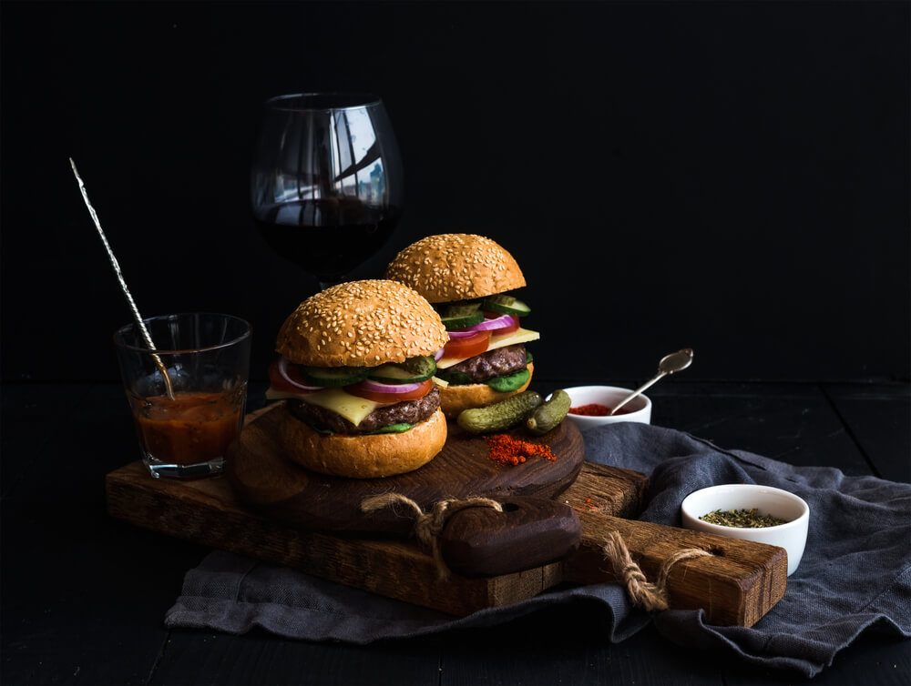 Fresh Beef Burgers on Rustic Wooden Boards With Glass of Wine and Tomato Sauce Black Background Selective Focus Closeup