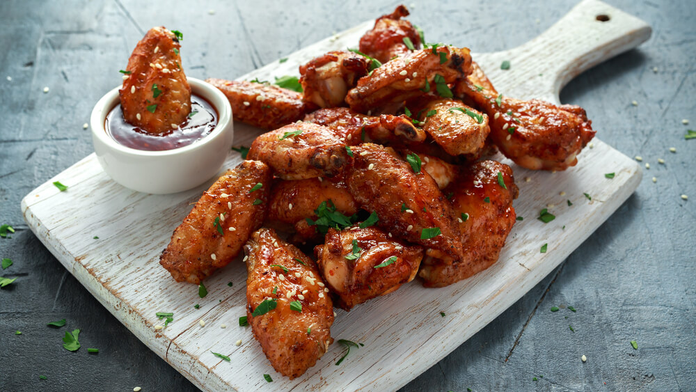 Baked Chicken Wings With Sesame Seeds and Sweet Chili Sauce on White Wooden Board