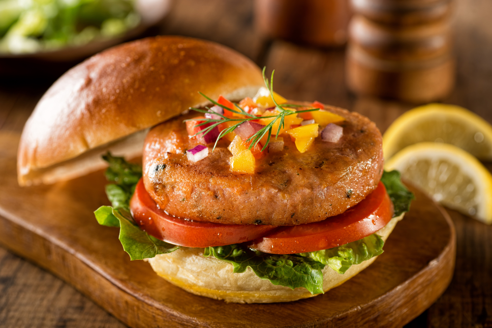 A Delicious Salmon Burger With Lettuce, Tomato and Pepper Salsa With Onion